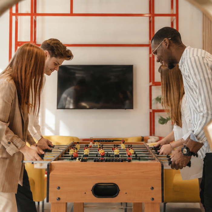 A group of friends playing on a foosball table in Airbnb peeping through a keyhole
