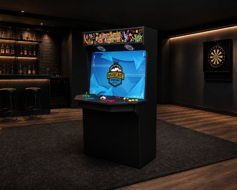 A freestanding arcade machine with a black cabinet and a bright blue game screen stands in a dimly lit modern room with wood flooring, a bar shelf, a dartboard, and wall lighting.