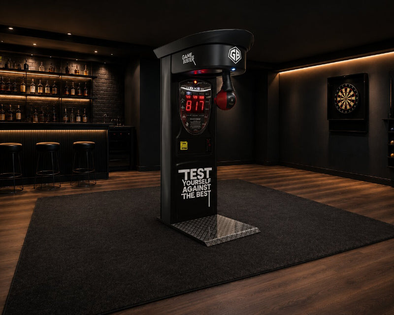A black boxing-style arcade machine or test machine stands on a dark rug in a dimly lit home bar or gaming room with wood flooring, shelves, stools, a dartboard, and wall lighting.