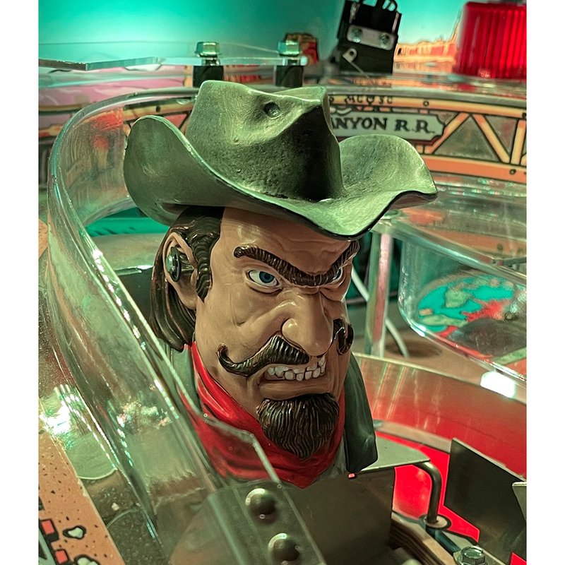 Chicago Gaming Cactus Canyon Remake Special Edition pinball machine featuring detailed outlaw character head with green cowboy hat and red bandana, commercial coin-operated game image