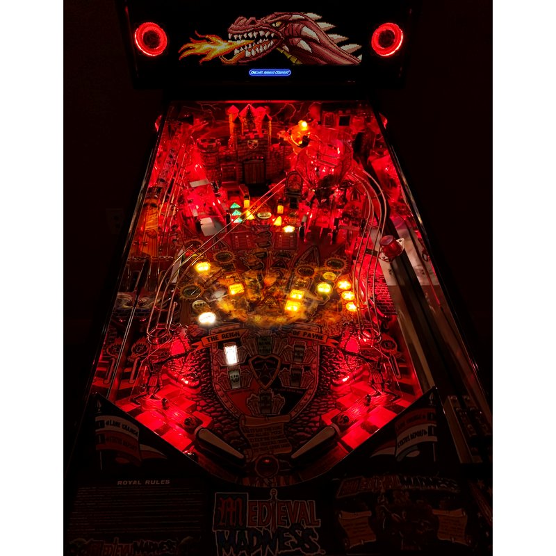 Chicago Gaming Medieval Madness Remake Merlin Edition pinball machine, home model, top-down view of illuminated playfield with lit ramps and bumpers