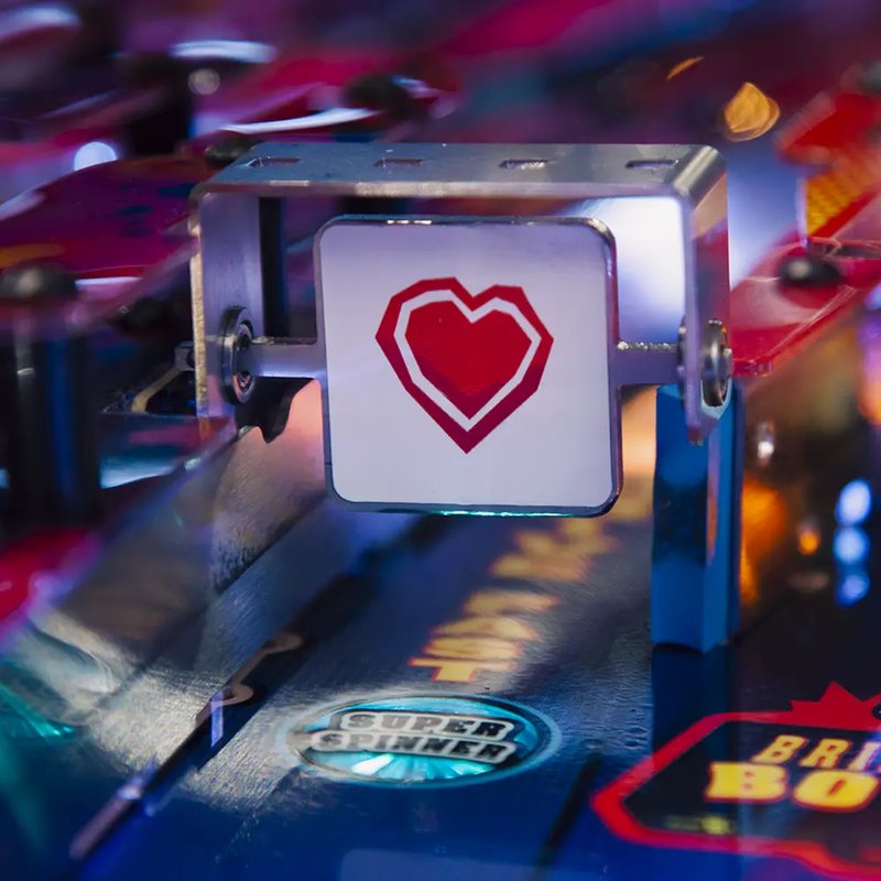 Chicago Gaming Pulp Fiction pinball machine with illuminated red heart symbol button in close-up view, commercial coin-operated arcade game image