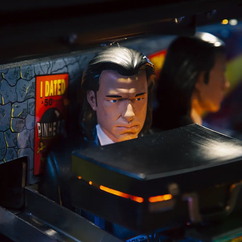 Chicago Gaming Pulp Fiction pinball machine commercial coin-operated game, showing illuminated playfield head with character figure and artwork detail image