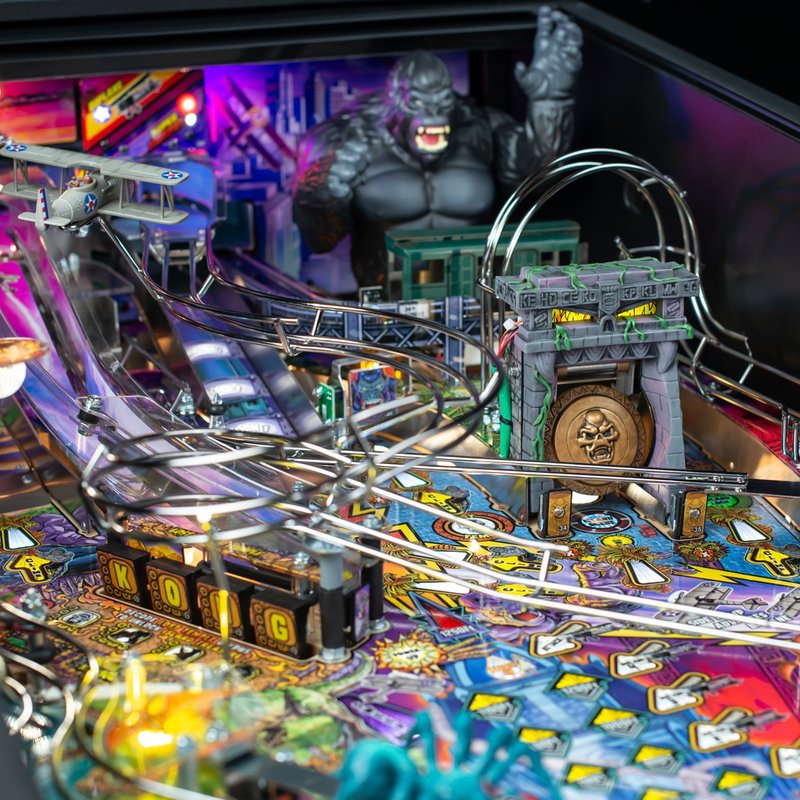 Stern King Kong Myth of Terror Island Premium Pinball Machine playfield detail showing animatronic Kong figure, temple gong toy, NYC train car lock, biplane ramp, and sculpted features.