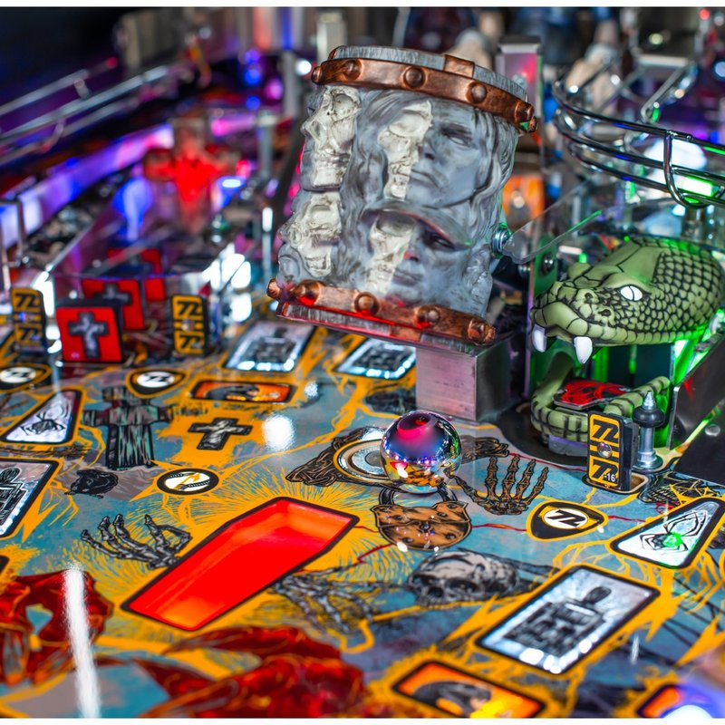 Stern Metallica Remastered Premium pinball machine playfield detail showing Sparky's Electric Chair sculpture, Grave Marker, and Snake feature with colorful artwork and illuminated elements.